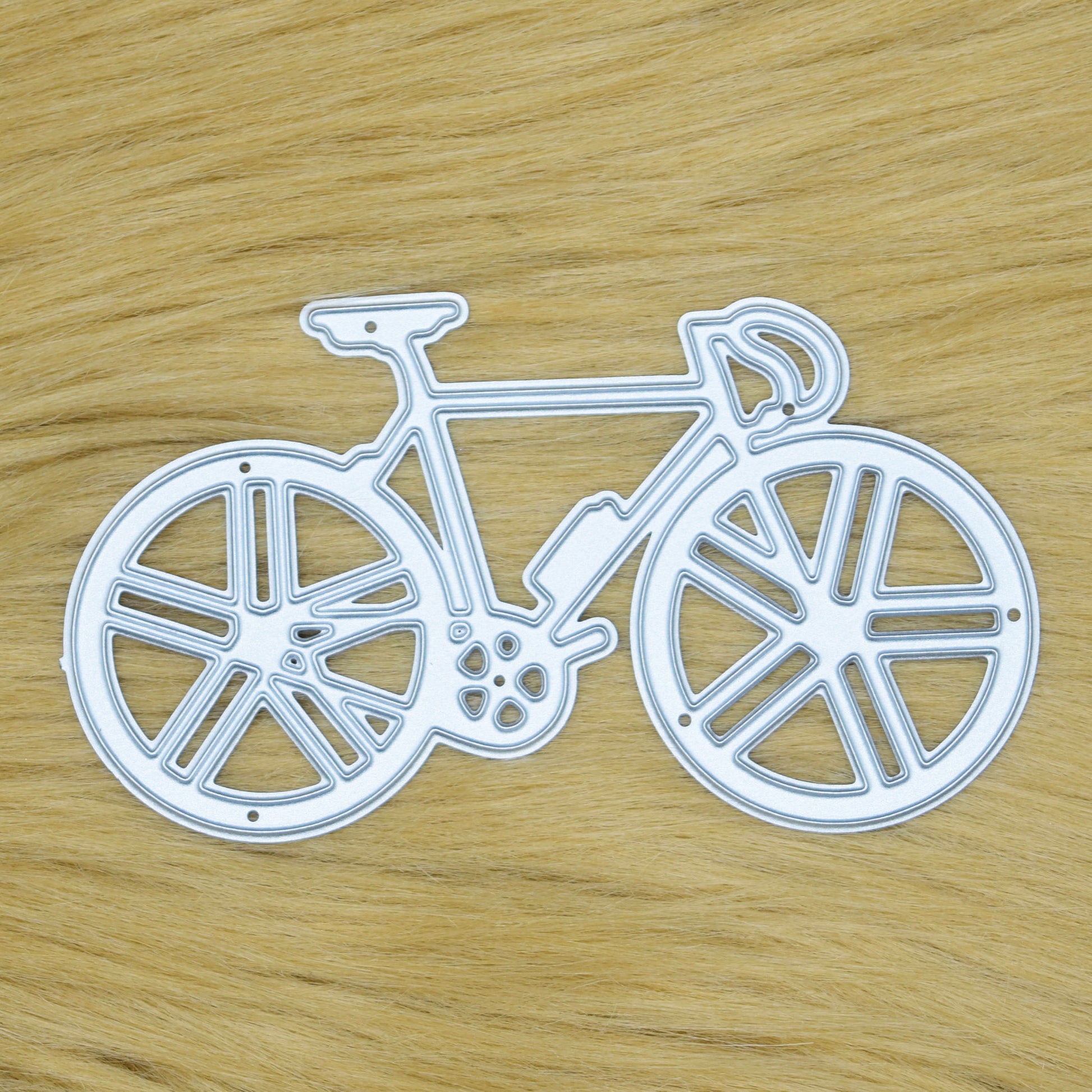 Racing bicycle metal cutting die displayed on a soft faux fur background for card making, scrapbooking and cycling-themed papercraft.