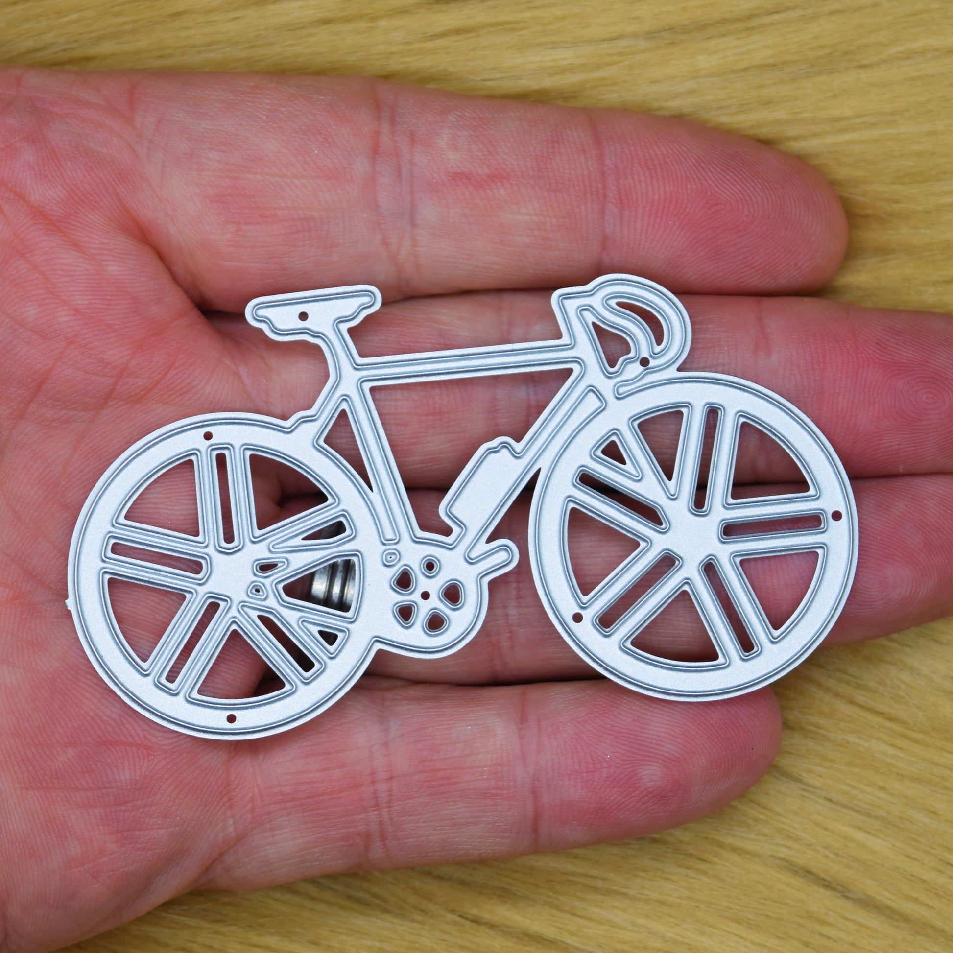 Racing bicycle metal cutting die shown in hand to demonstrate its size for handmade cards and papercraft projects.