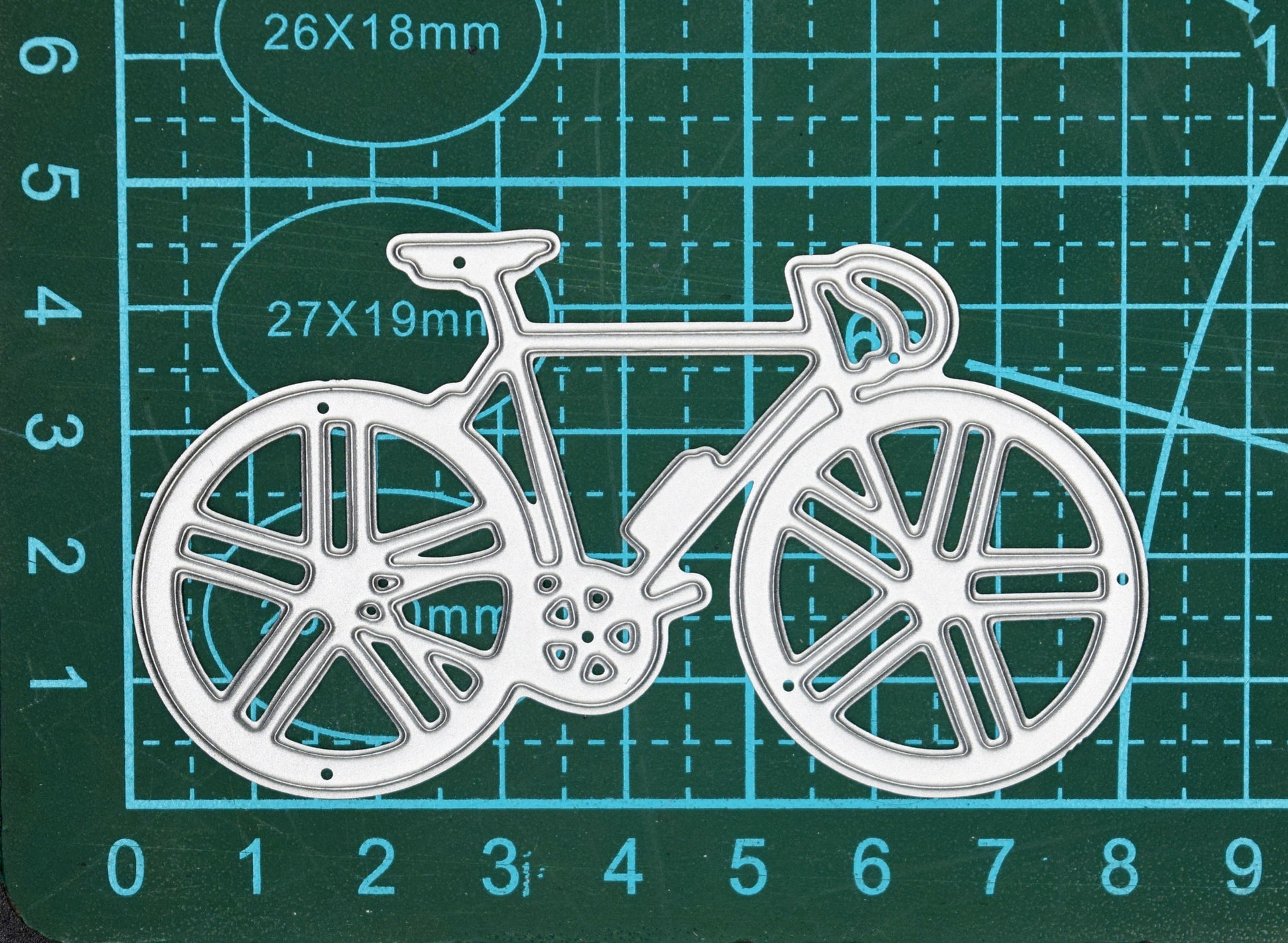 Racing bicycle metal cutting die displayed on a centimetre cutting mat to show scale for card making and papercraft.
