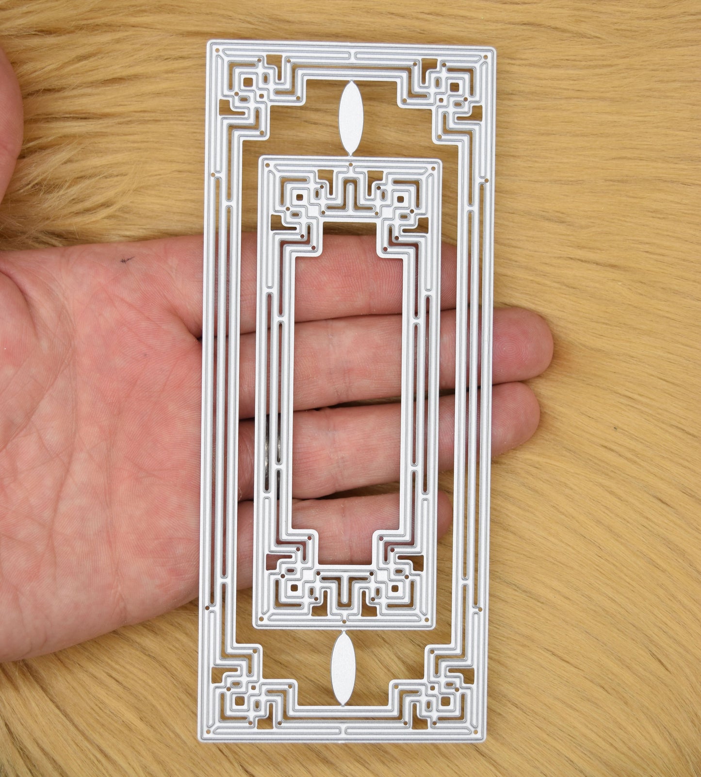 Art Deco rectangle metal cutting dies shown in hand for size reference
