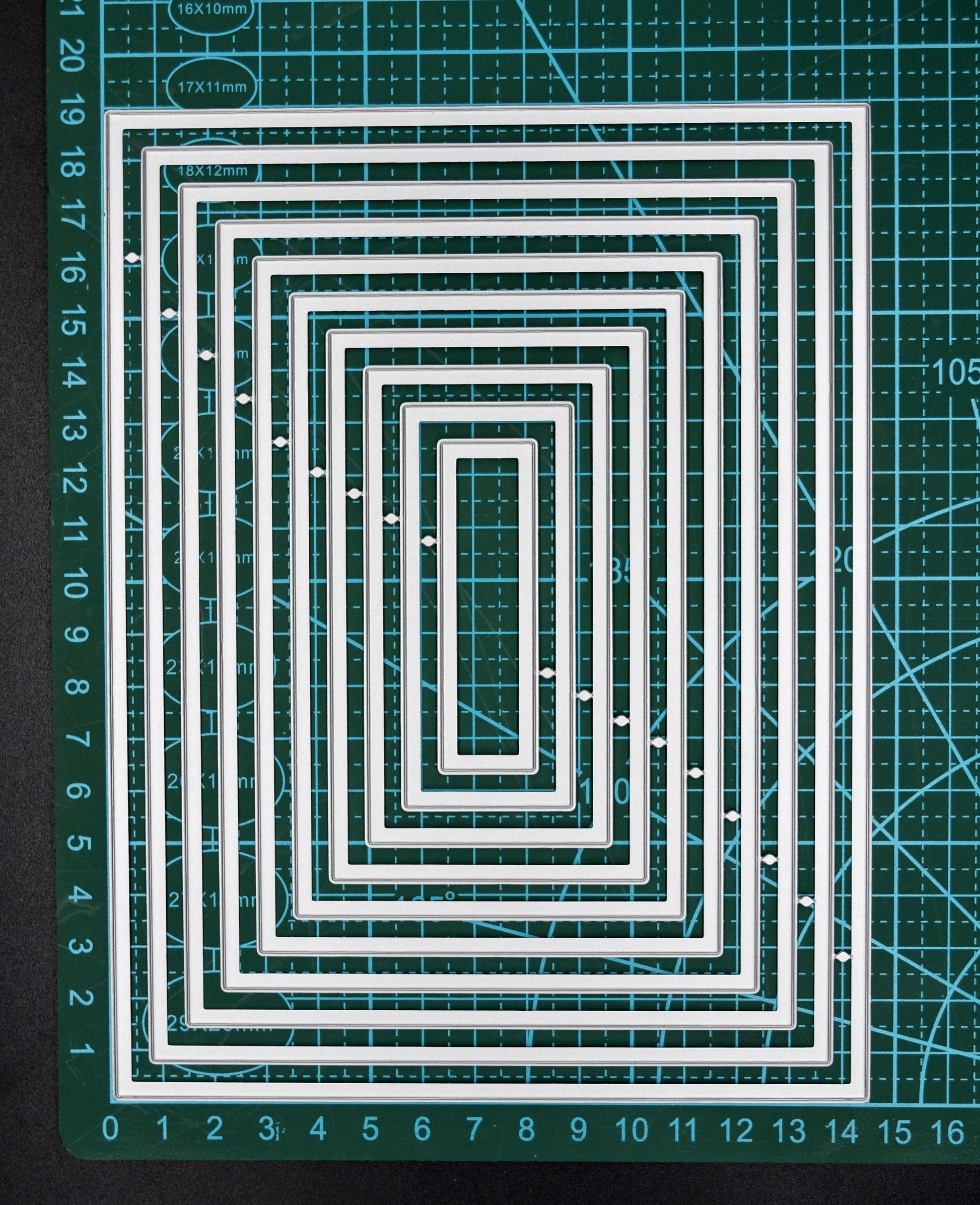Rectangle nesting metal cutting dies on measured cutting mat showing graduated nesting sizes