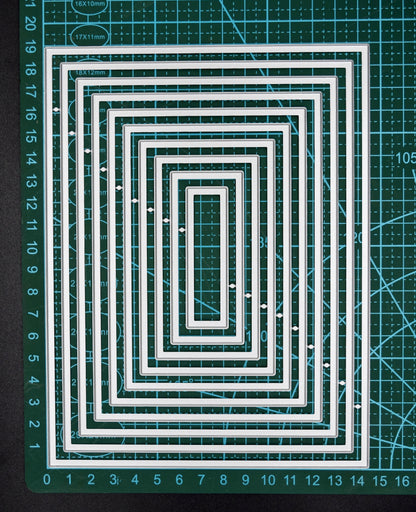 Rectangle nesting metal cutting dies on measured cutting mat showing graduated nesting sizes
