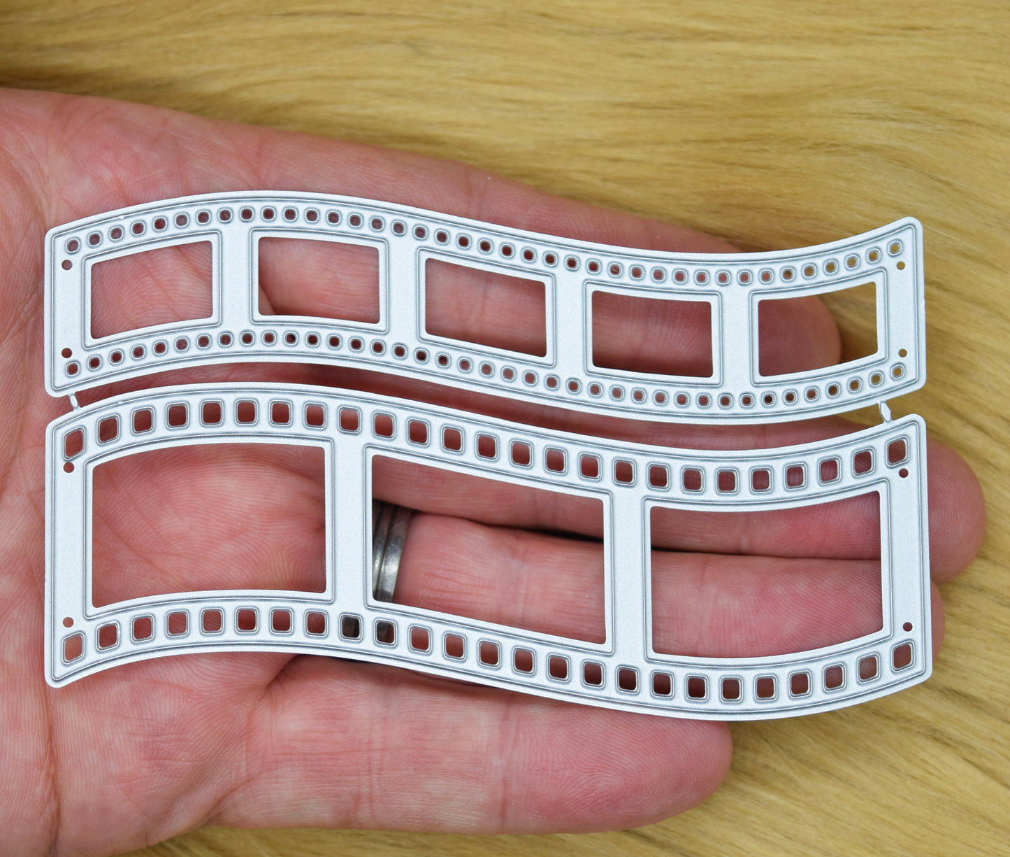 Retro film strip metal cutting dies shown in hand to demonstrate the size of the two-piece set