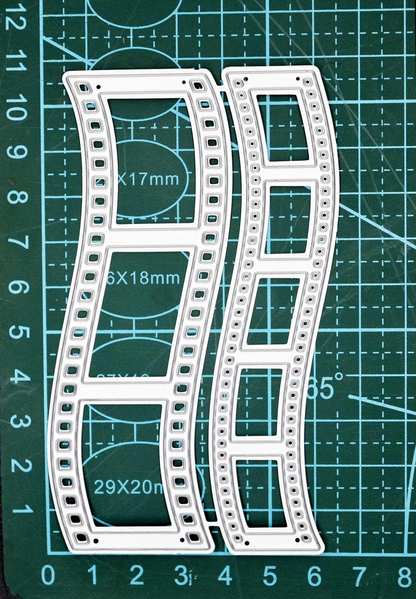 Retro film strip metal cutting dies displayed on a cutting mat for size reference