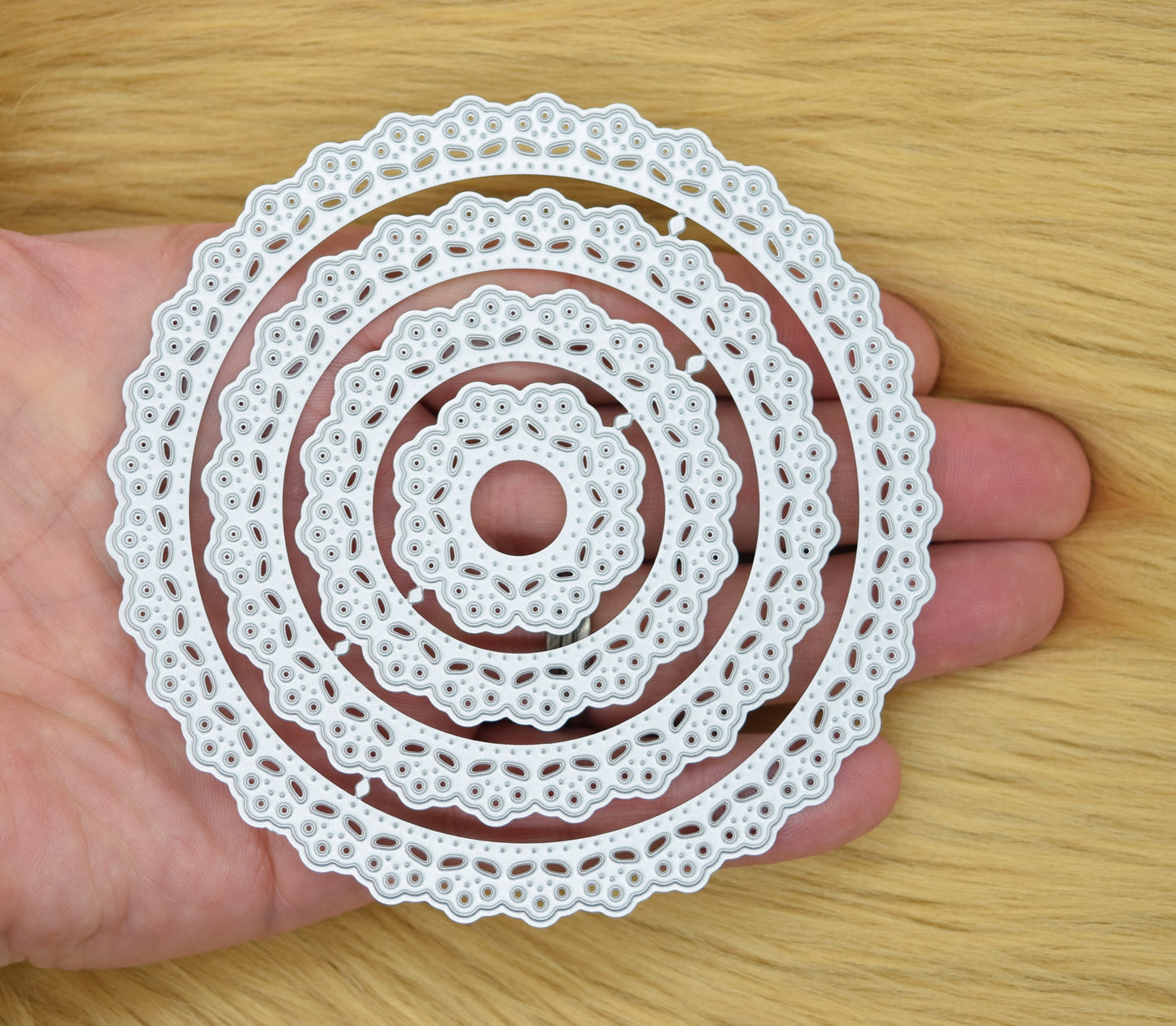 Set of round lace patterned nesting metal cutting dies held in hand showing size