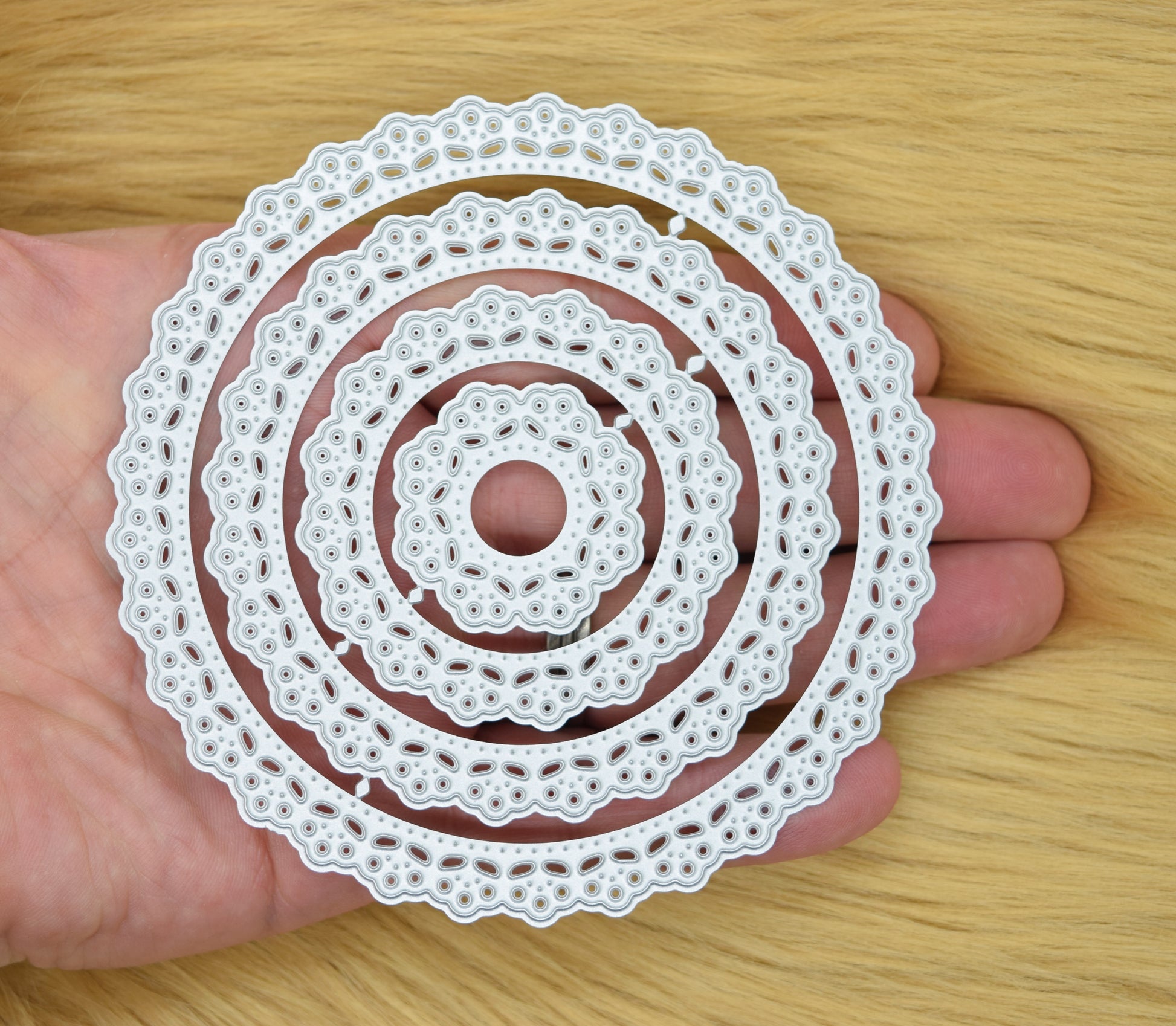 Set of round lace patterned nesting metal cutting dies held in hand showing size