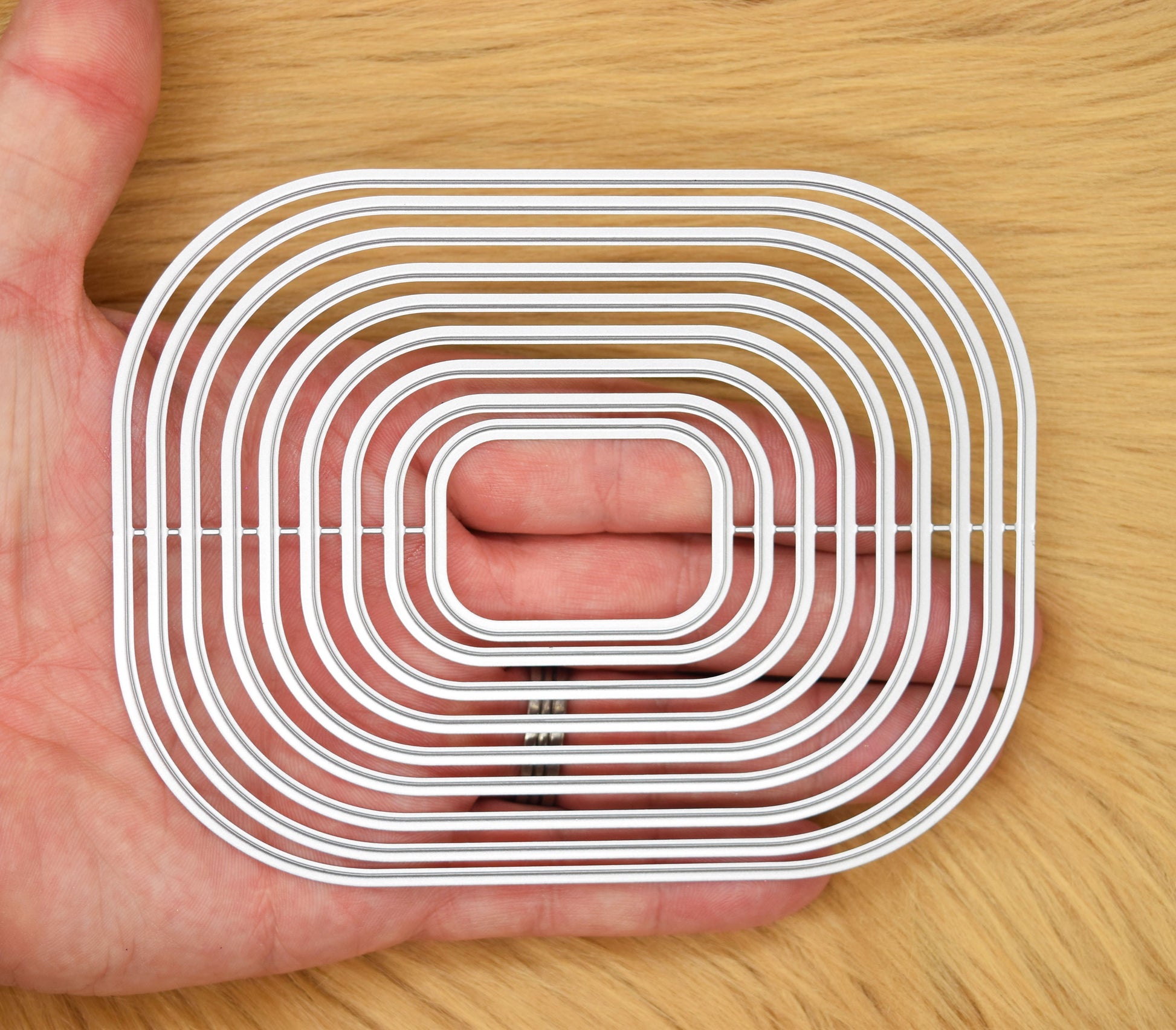 Rounded corner rectangle nesting cutting dies shown in hand for size reference