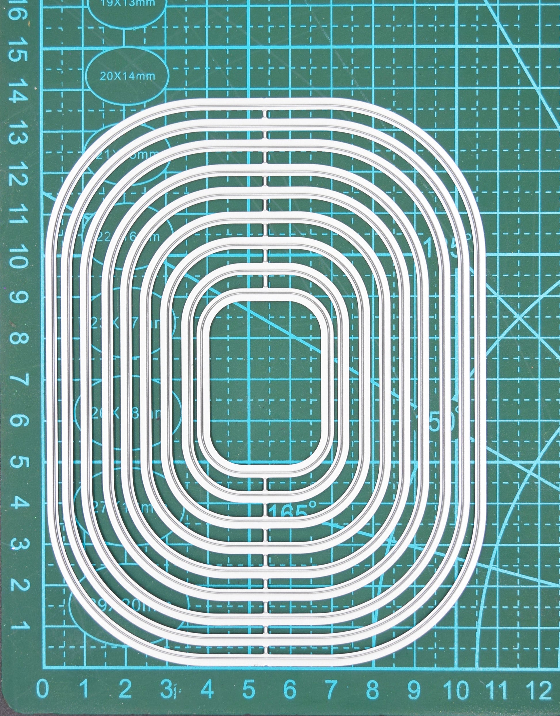 Rounded corner rectangle nesting metal cutting dies set on measuring mat showing size scale