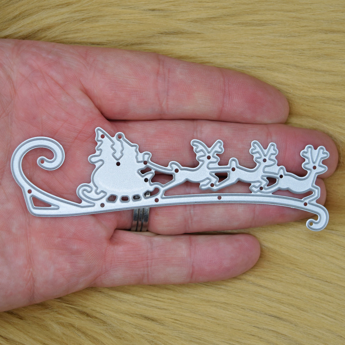 Santa sleigh and reindeer metal cutting die shown in hand for size comparison