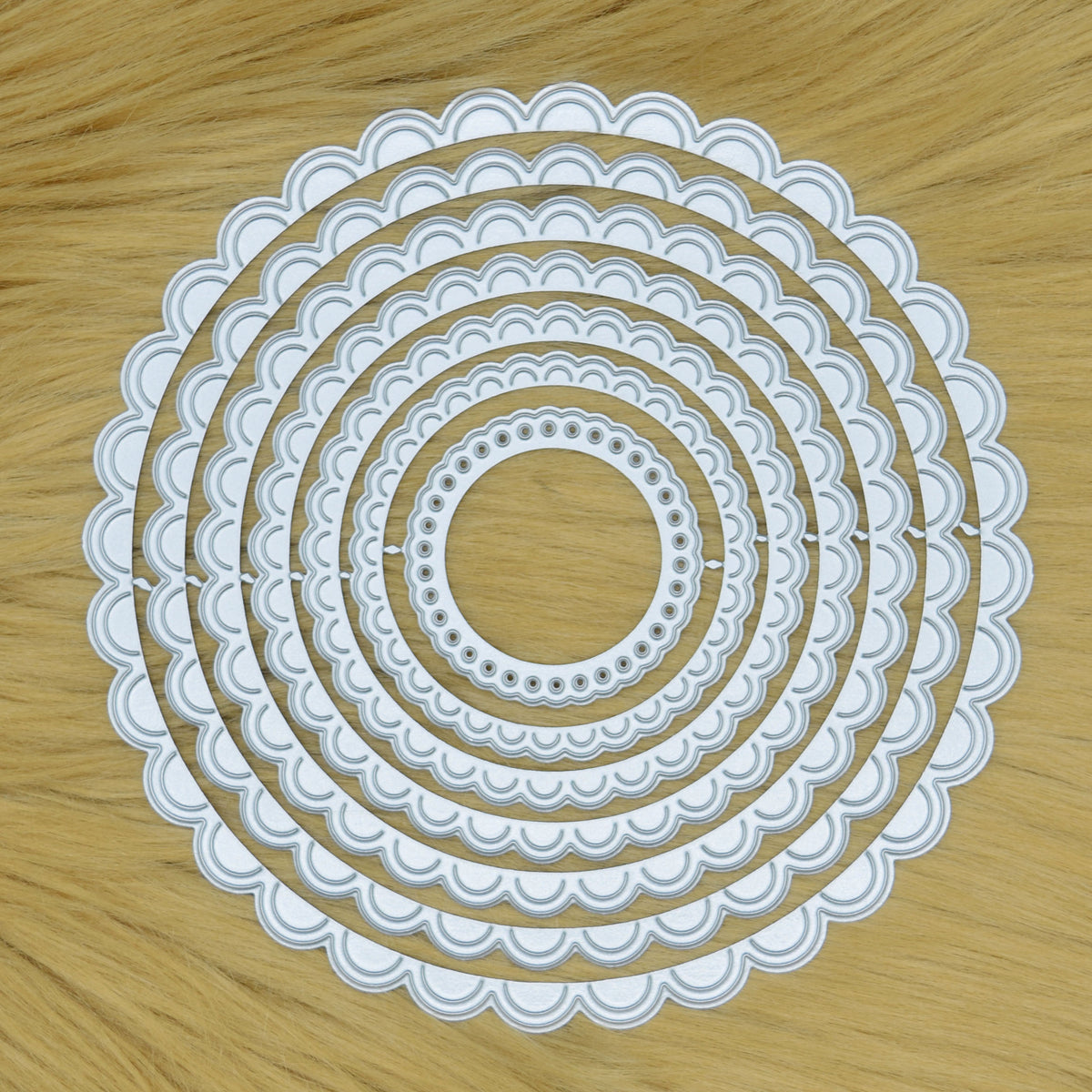 Scalloped circle nesting metal cutting die set displayed on faux fur background