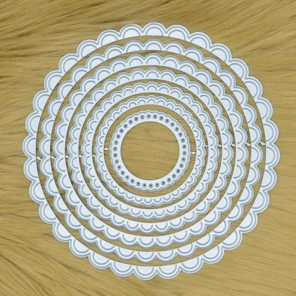 Scalloped circle nesting metal cutting die set displayed on faux fur background