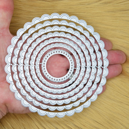 Scalloped circle nesting dies shown in hand for scale and size comparison