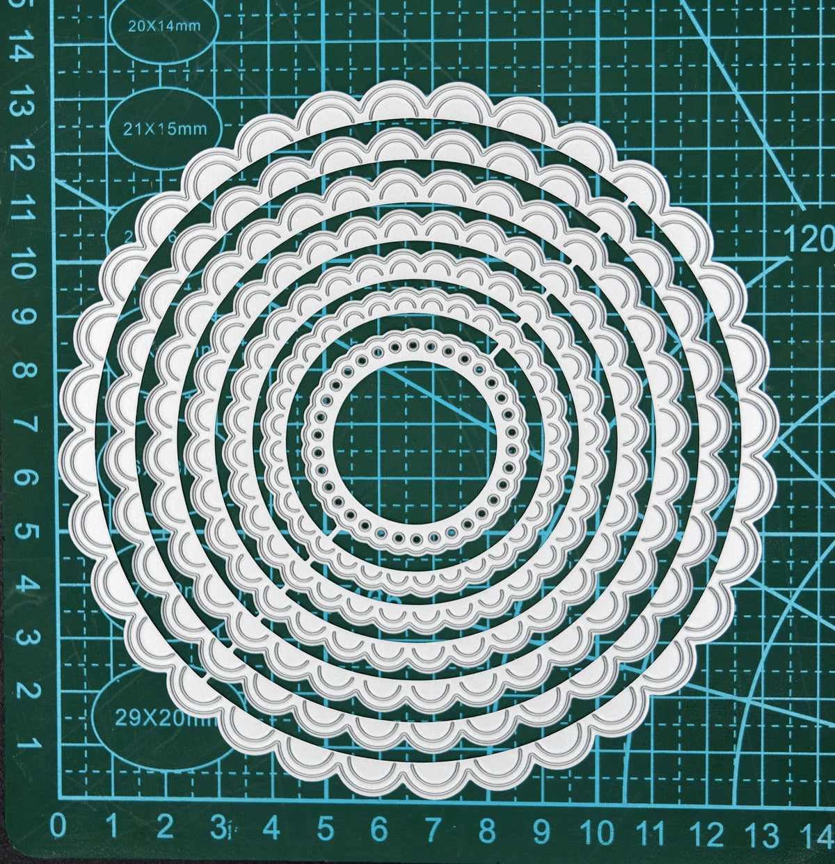 Scalloped circle nesting metal cutting dies shown on cutting mat for size reference