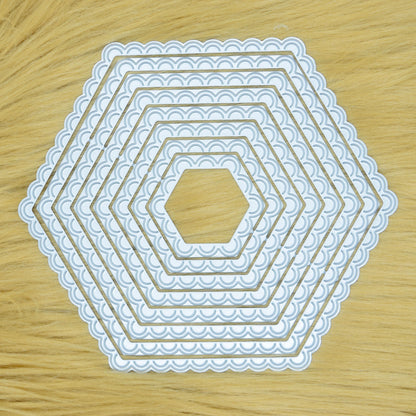 Graduated scalloped hexagon nesting metal cutting dies displayed on a light faux fur background for card making and papercraft.