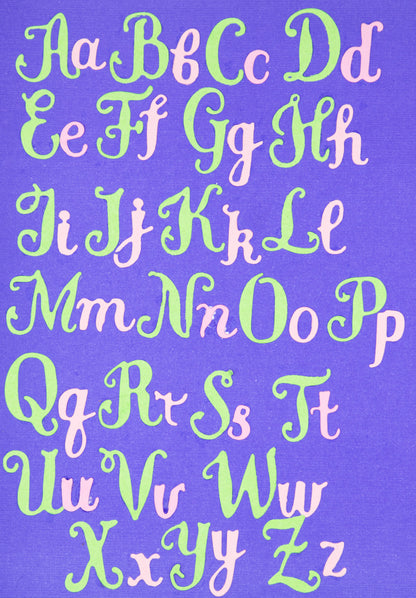 Decorative uppercase and lowercase script alphabet cuts arranged on purple cardstock for card making and papercraft