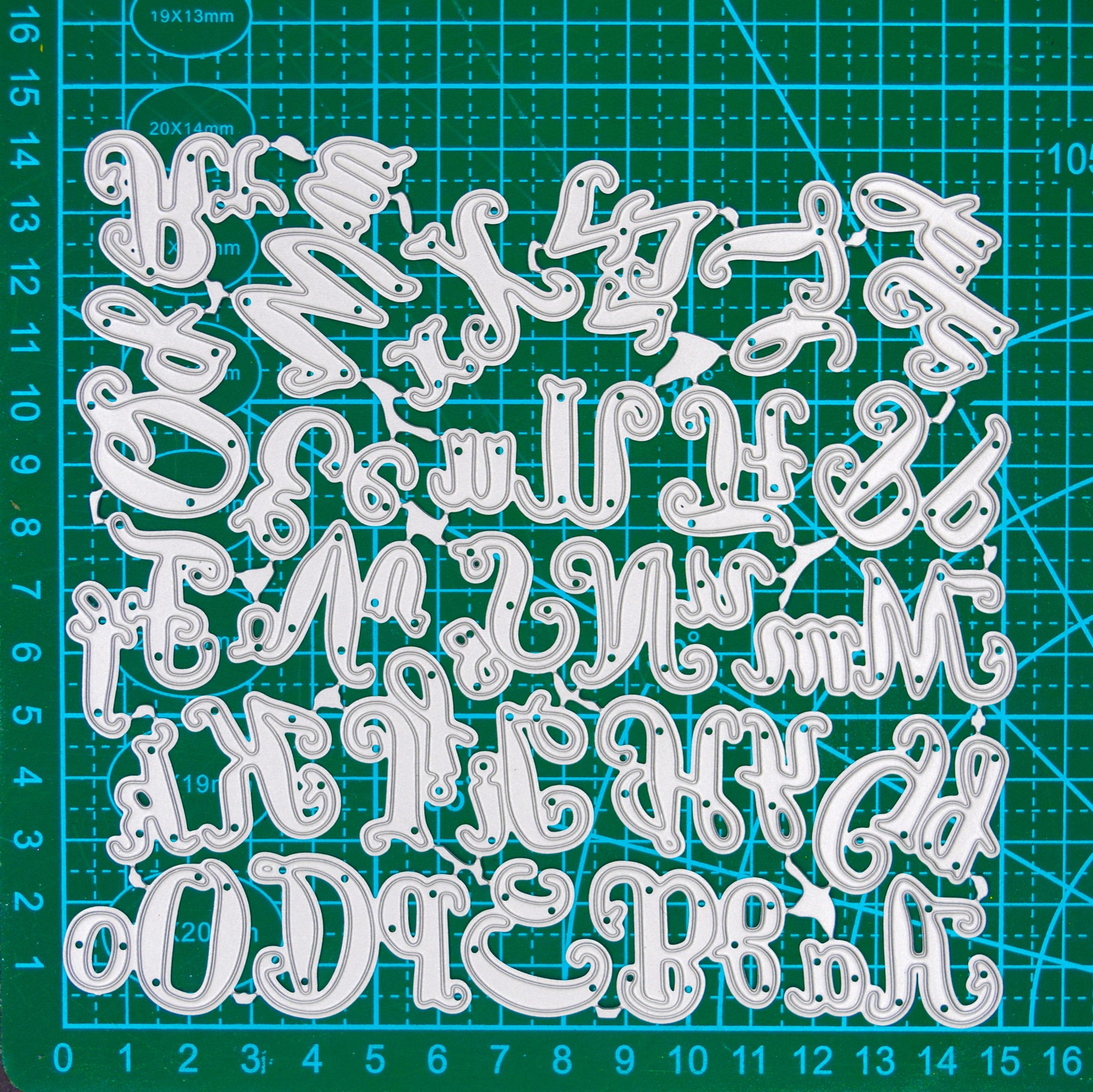 Uppercase and lowercase script alphabet metal cutting dies displayed on a centimetre cutting mat for size reference