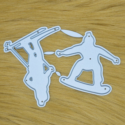 Skier and snowboarder metal cutting dies displayed on a soft faux fur background for winter-themed card making and scrapbooking.