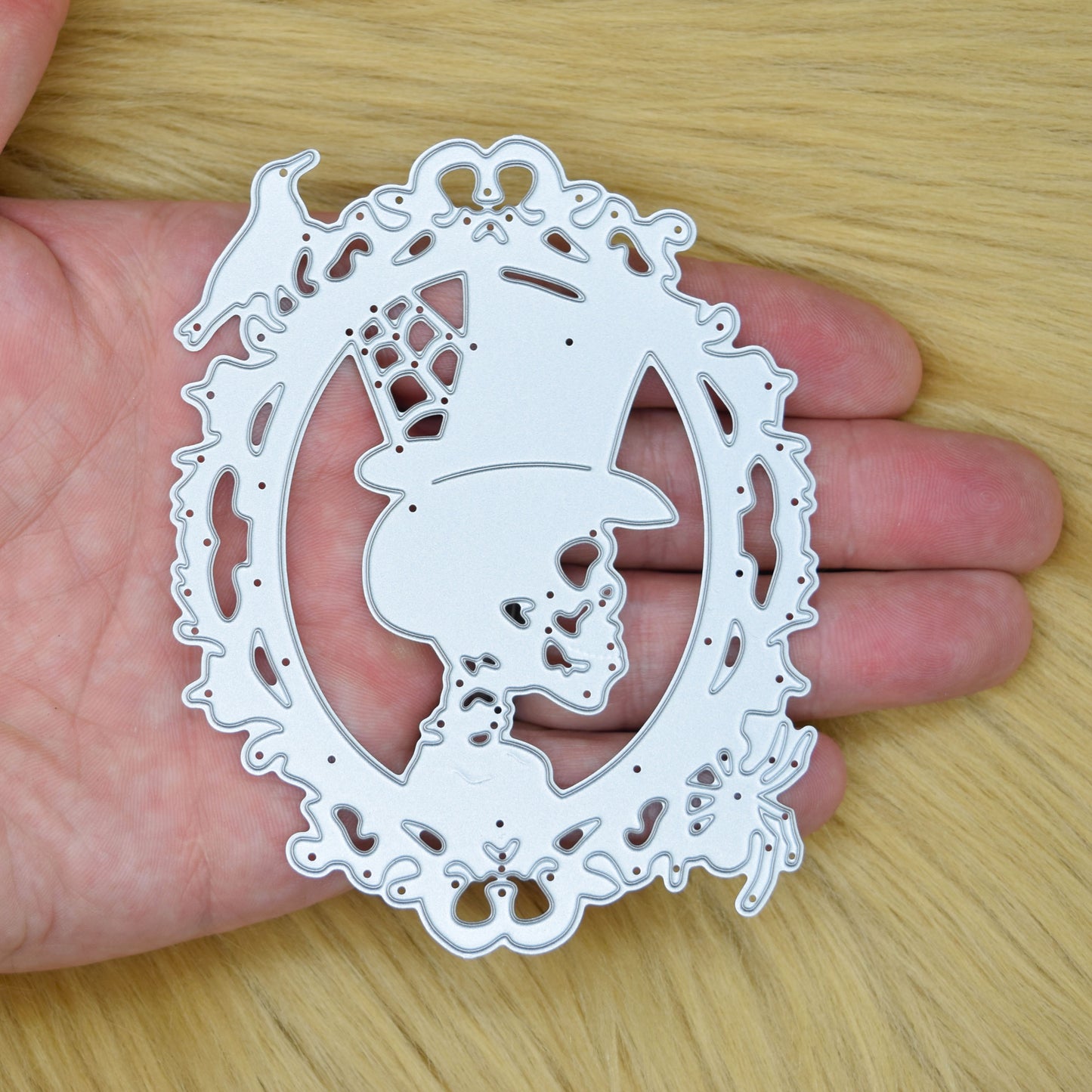 Skull cameo frame metal cutting die shown in hand for size reference