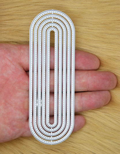Slimline oval nesting dies held in hand showing scale and elongated frame shape