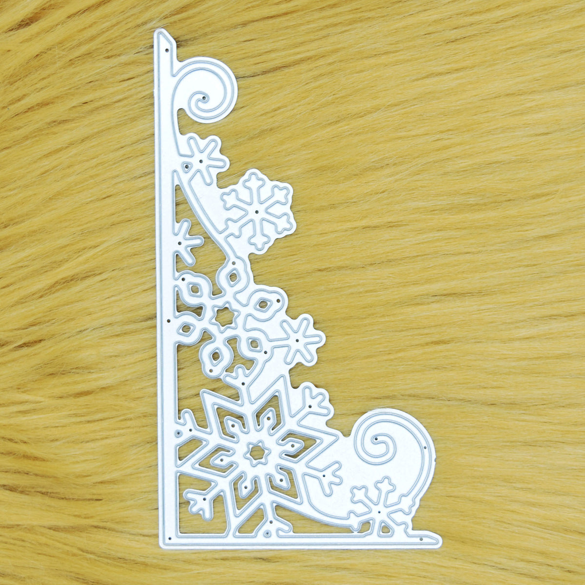 Large snowflake corner border metal cutting die displayed on a tan faux fur background for card making and Christmas papercraft.