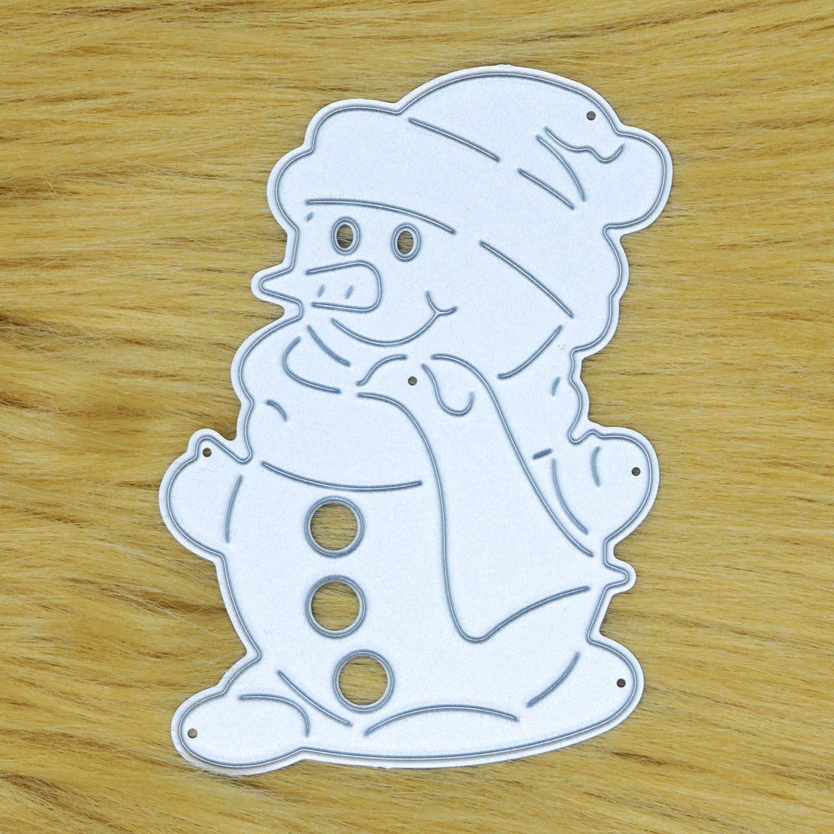 Snowman metal cutting die on a tan faux fur background, showing the cutting face and fine details for festive papercraft.
