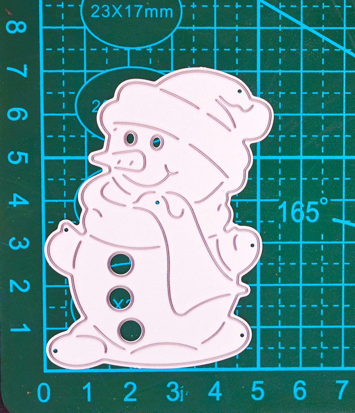 Snowman metal cutting die on a centimetre cutting mat, showing the hat, scarf, mitten and button details.