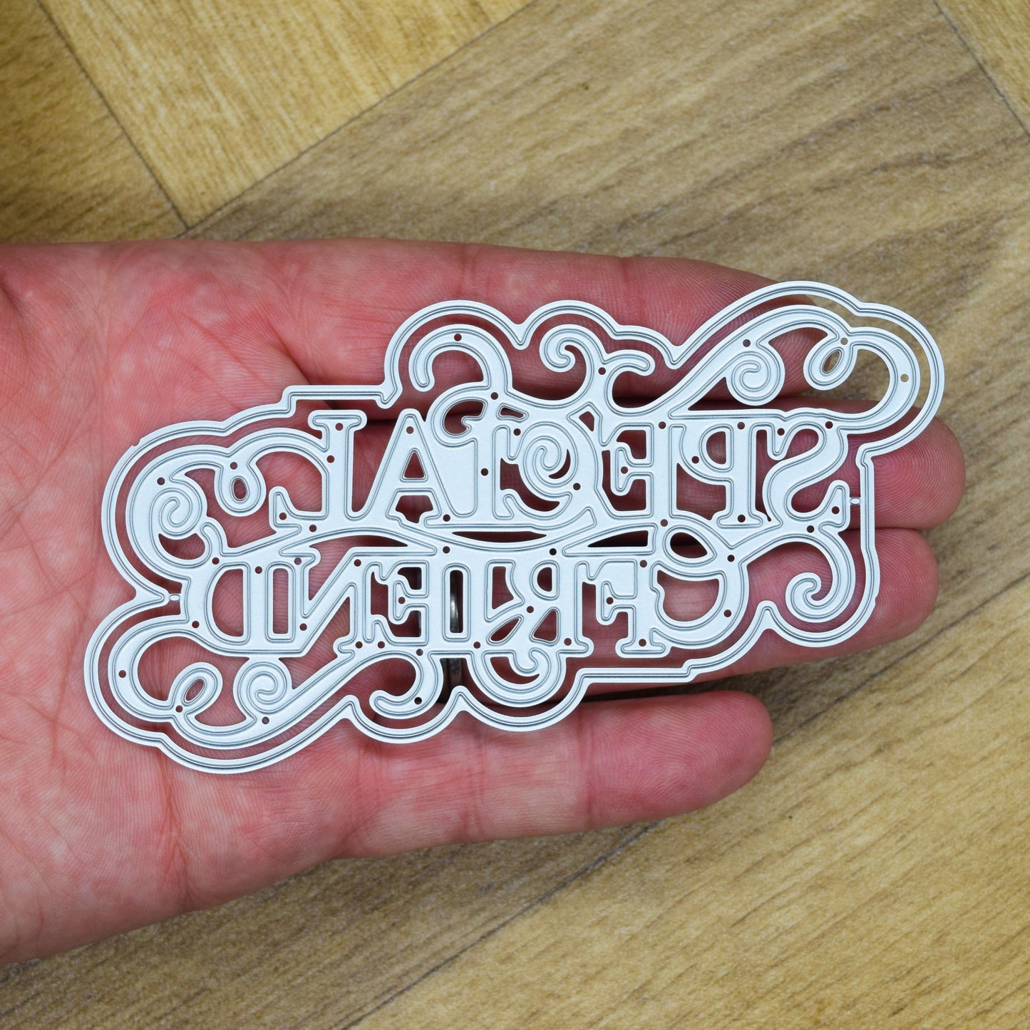 Detailed Special Friend layered sentiment metal cutting dies held in hand to show their size and intricate scrollwork.