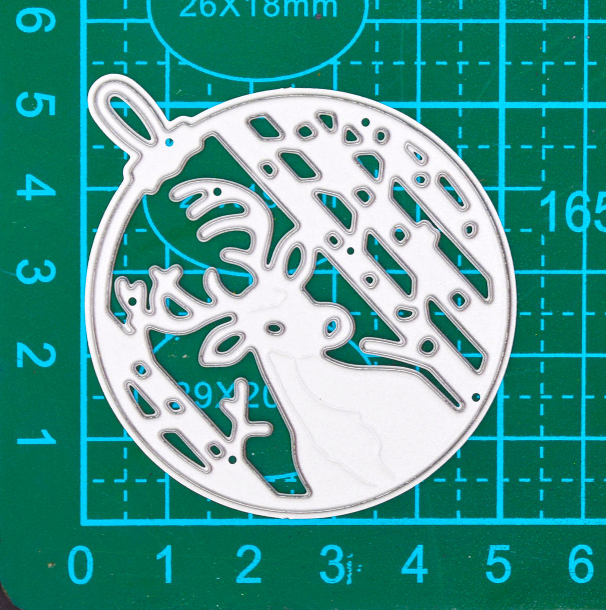 Stag woodland bauble metal cutting die placed diagonally on a centimetre cutting mat for size reference.