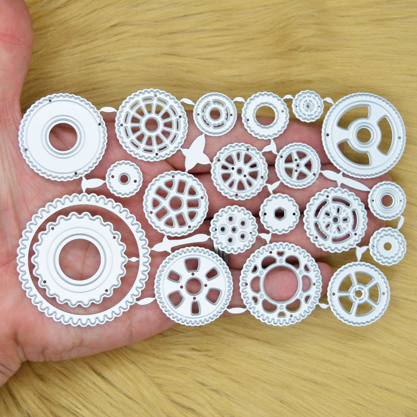 Steampunk cogs metal cutting dies shown in hand to demonstrate the size of the 20-piece set