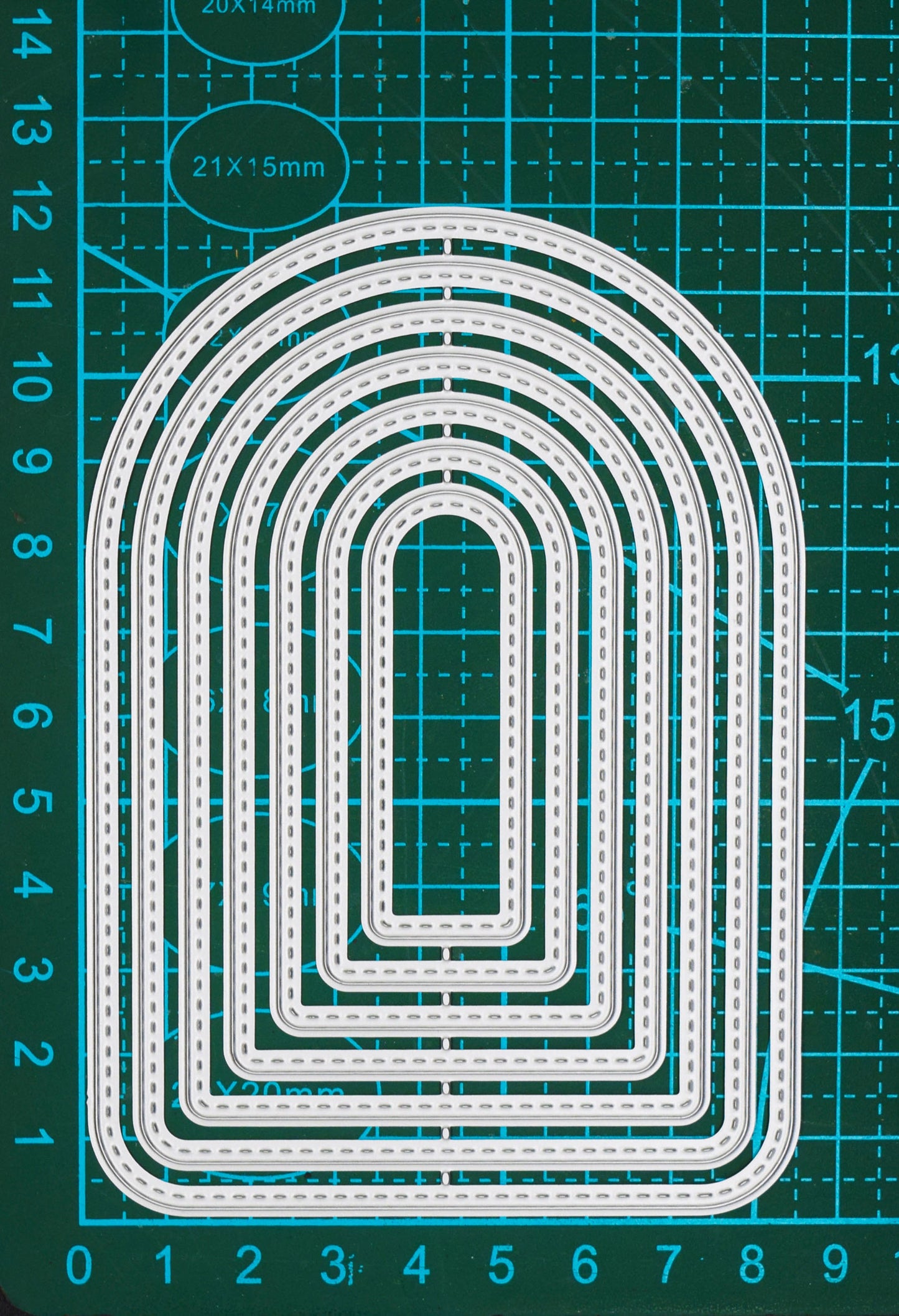 Seven graduated stitched arch metal cutting dies shown on a centimetre cutting mat for clear size comparison.