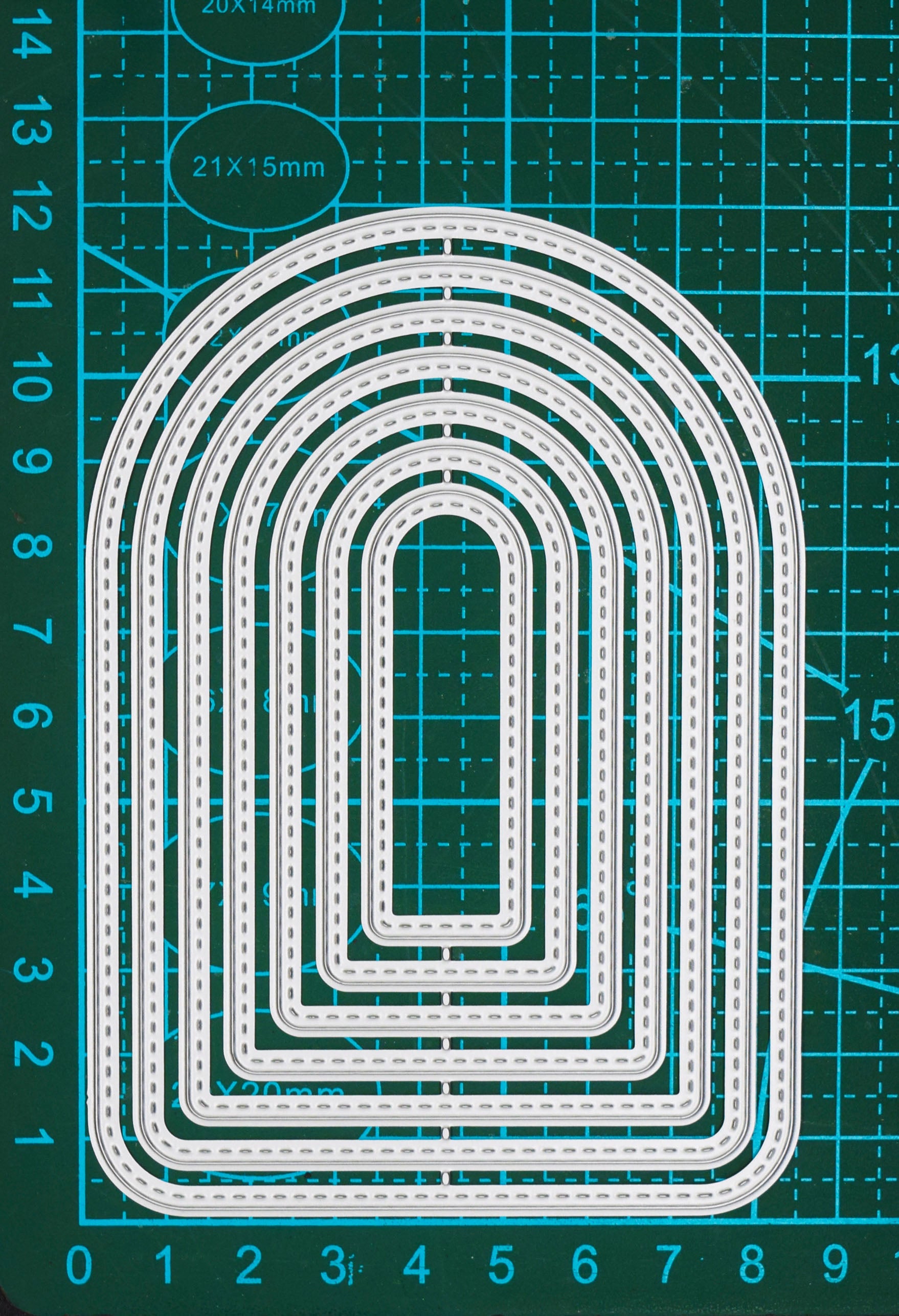 Seven graduated stitched arch metal cutting dies shown on a centimetre cutting mat for clear size comparison.