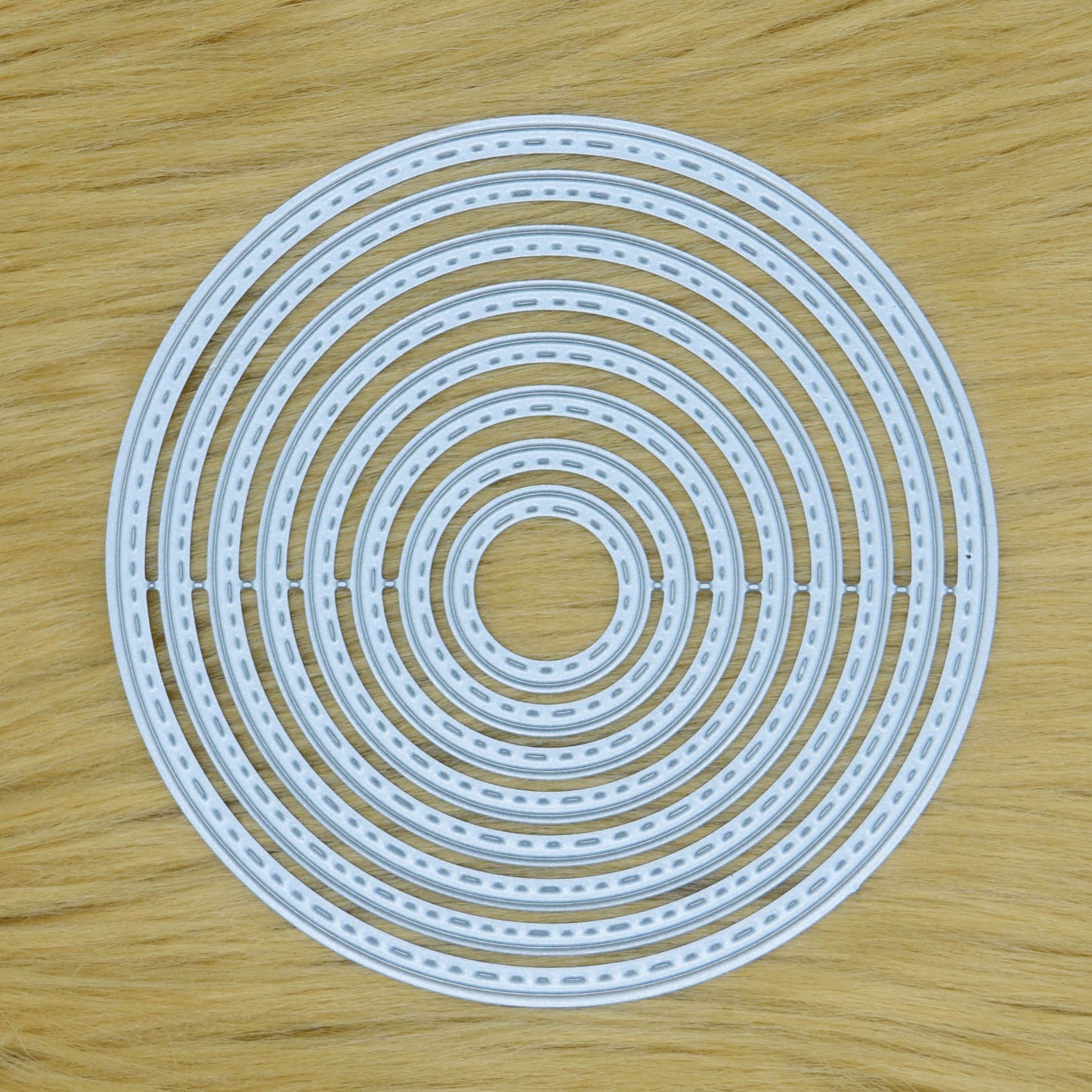 Set of eight stitched circle nesting metal cutting dies displayed together on a tan faux fur background.