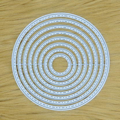 Set of eight stitched circle nesting metal cutting dies displayed together on a tan faux fur background.