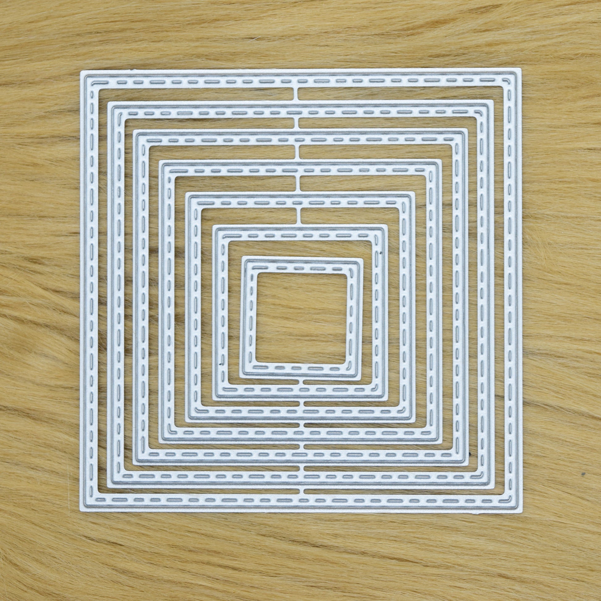 Stitched square metal cutting dies set on faux fur background