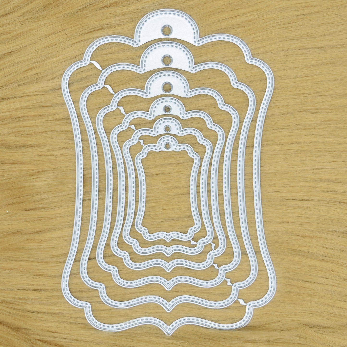 Elegant stitched tag nesting metal cutting dies set on wooden background