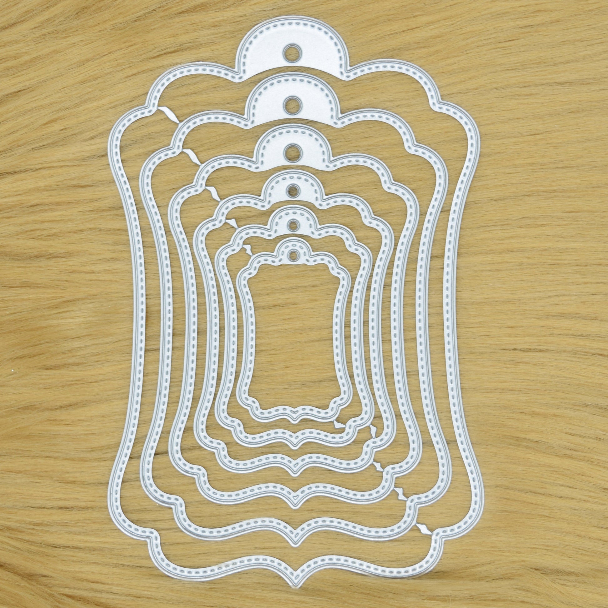 Elegant stitched tag nesting metal cutting dies set on wooden background