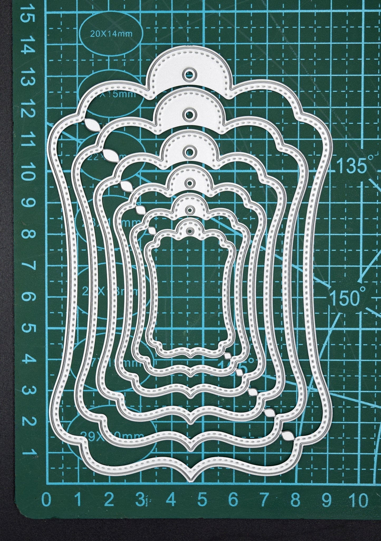 Stitched tag nesting dies on cutting mat showing size