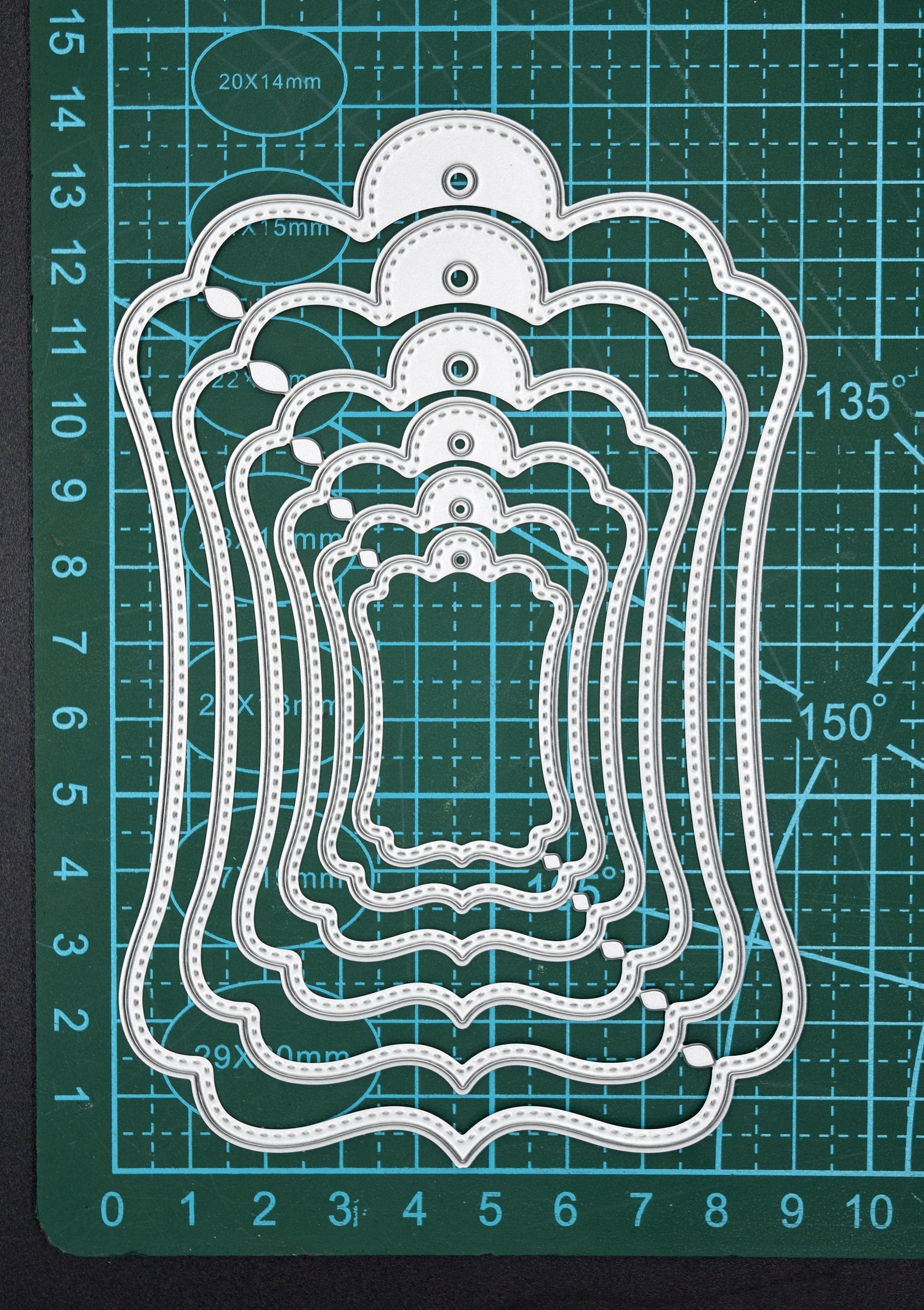 Stitched tag nesting dies on cutting mat showing size