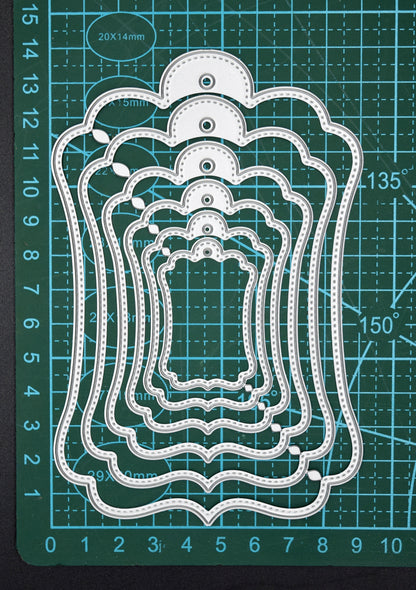 Stitched tag nesting dies on cutting mat showing size