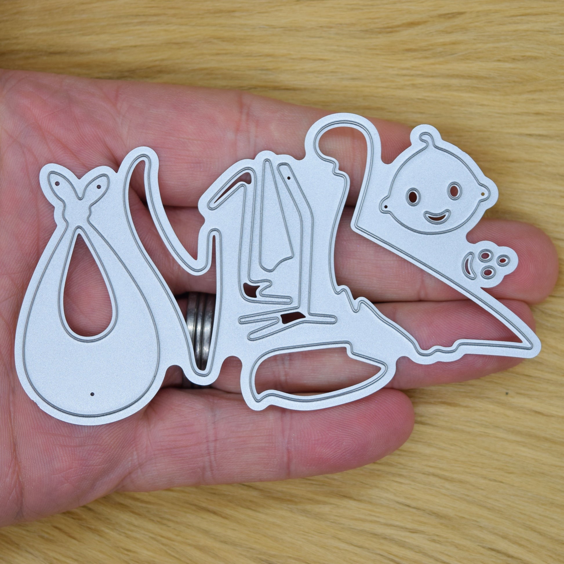 Stork and baby metal cutting dies shown in hand for size