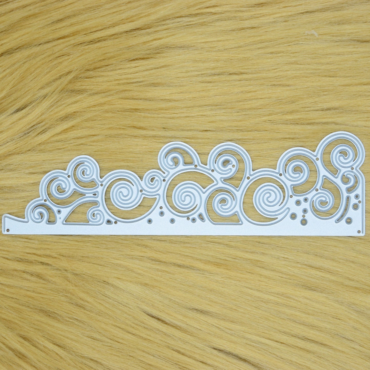 Decorative swirly waves metal cutting die held in hand to show its size and detailed spiral design