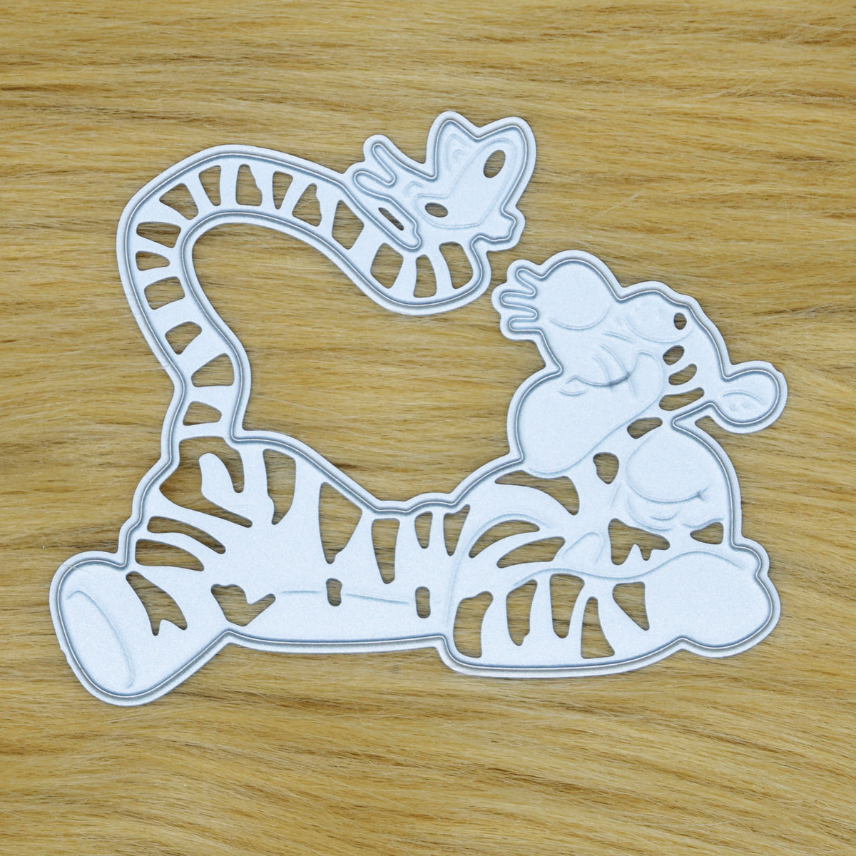 Tigger metal cutting die on a tan faux fur background, showing the cutting face and striped details for papercraft.