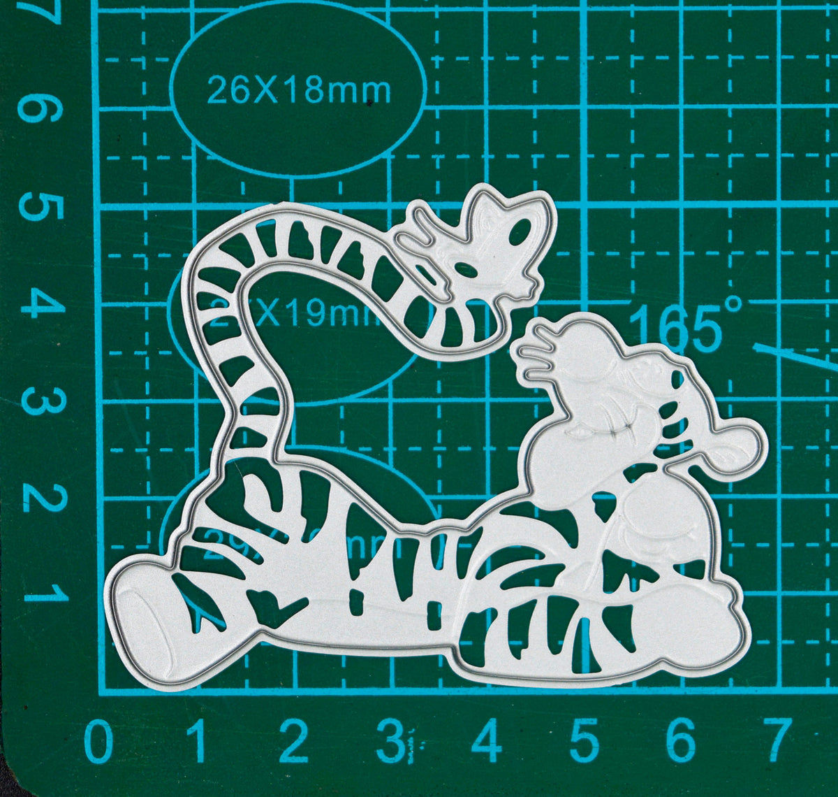 Tigger character metal cutting die on a centimetre cutting mat, showing its curled tail and body details.