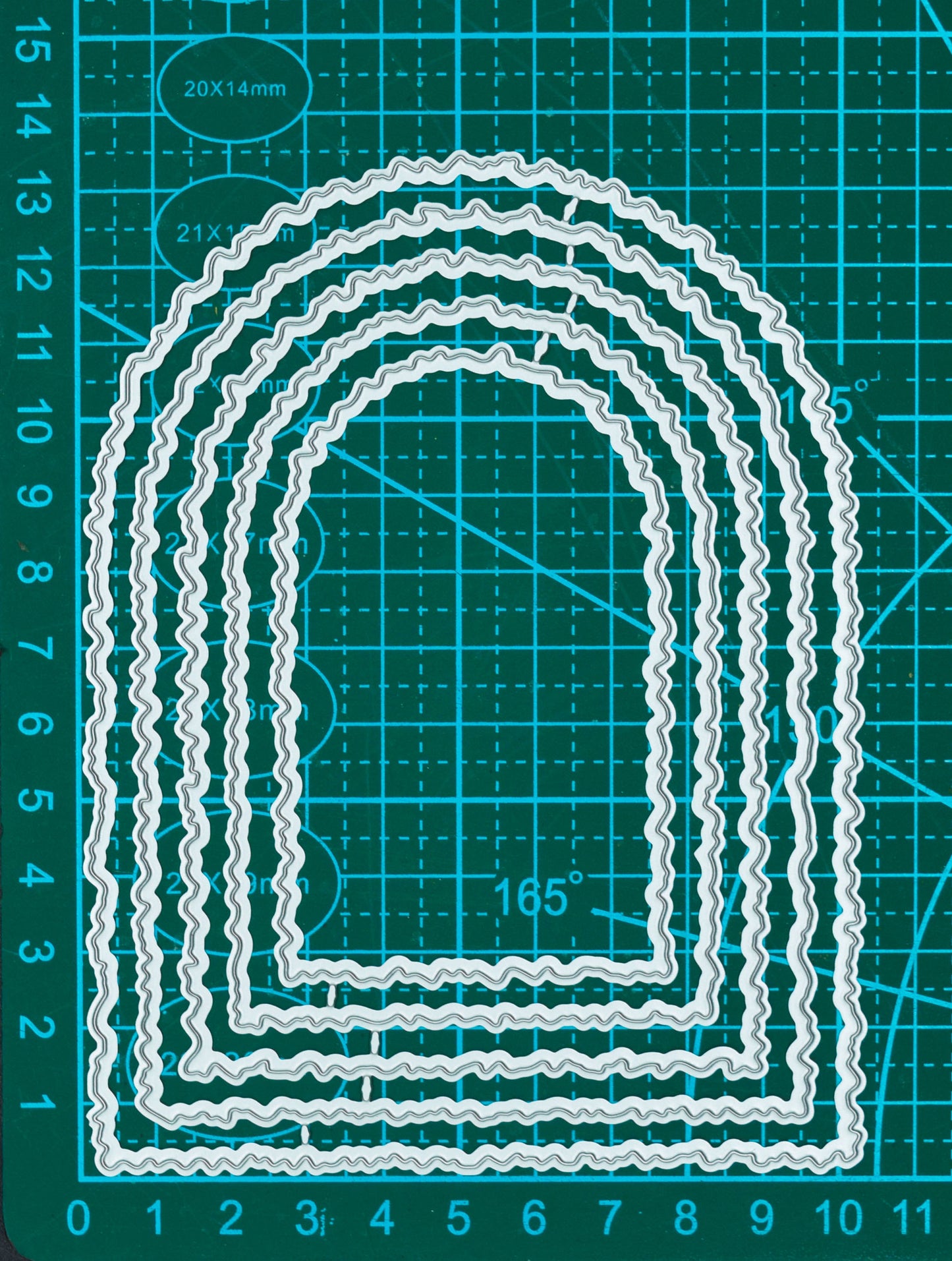 Torn edge arch nesting metal cutting dies displayed on a measurement mat for scale, showing five graduated arch shapes.