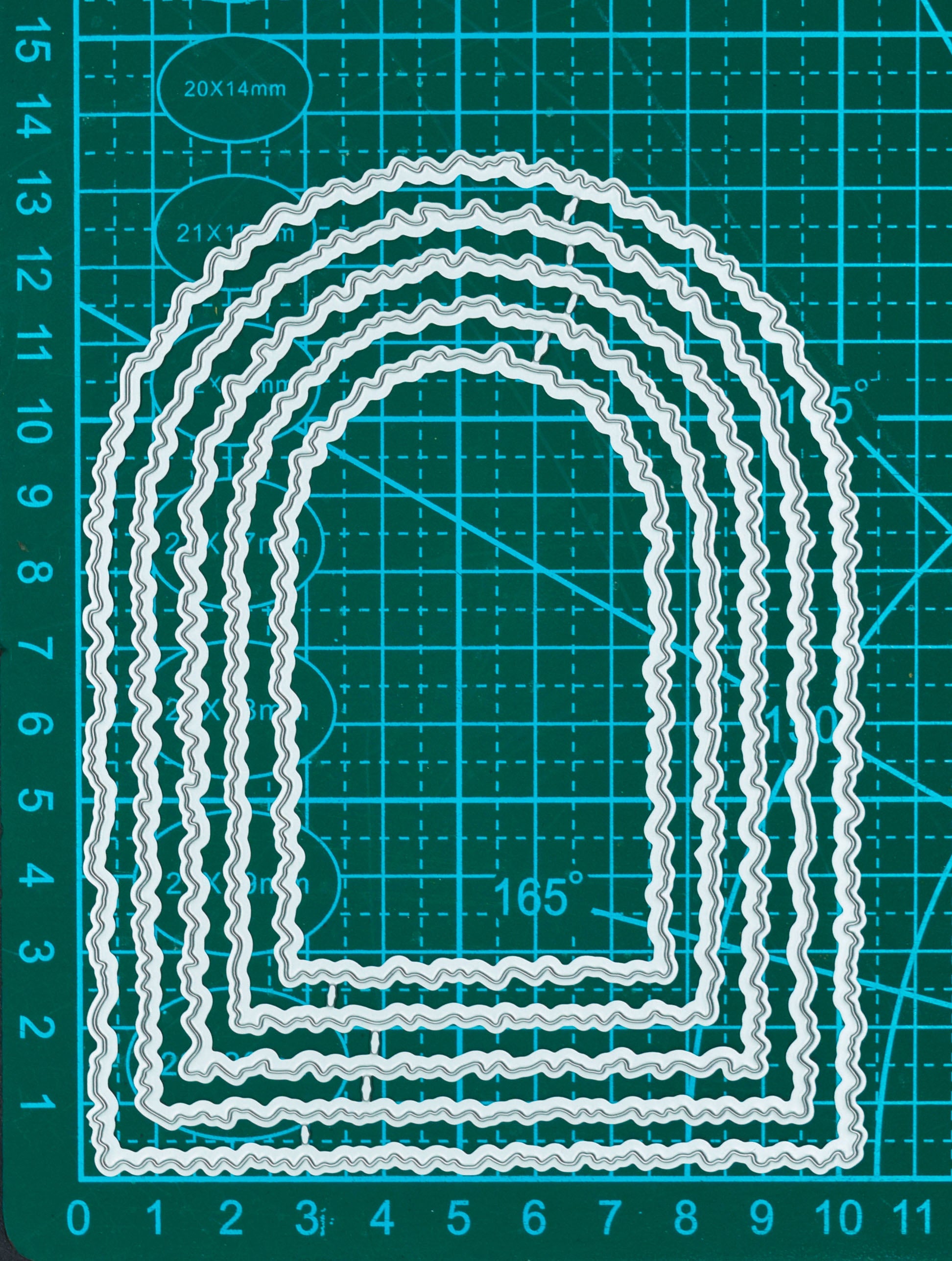 Torn edge arch nesting metal cutting dies displayed on a measurement mat for scale, showing five graduated arch shapes.