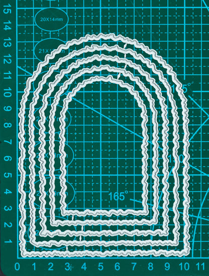 Torn edge arch nesting metal cutting dies displayed on a measurement mat for scale, showing five graduated arch shapes.