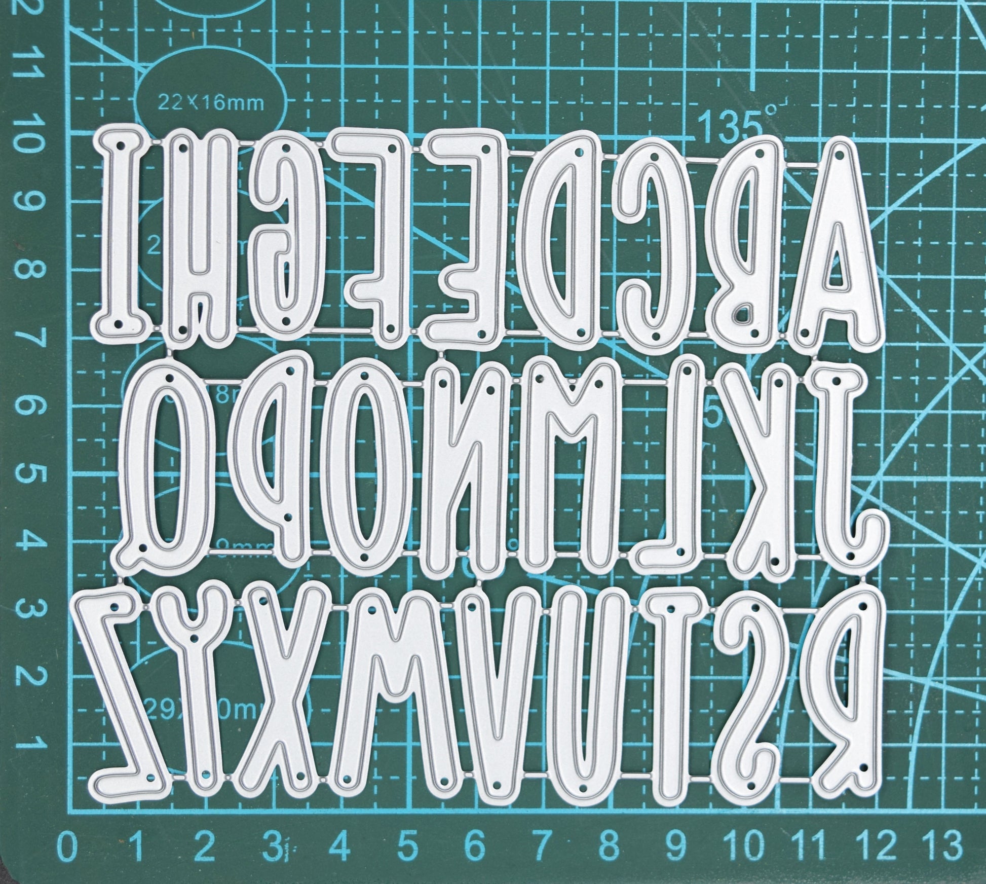 Uppercase alphabet metal cutting dies set shown on measuring mat for size reference