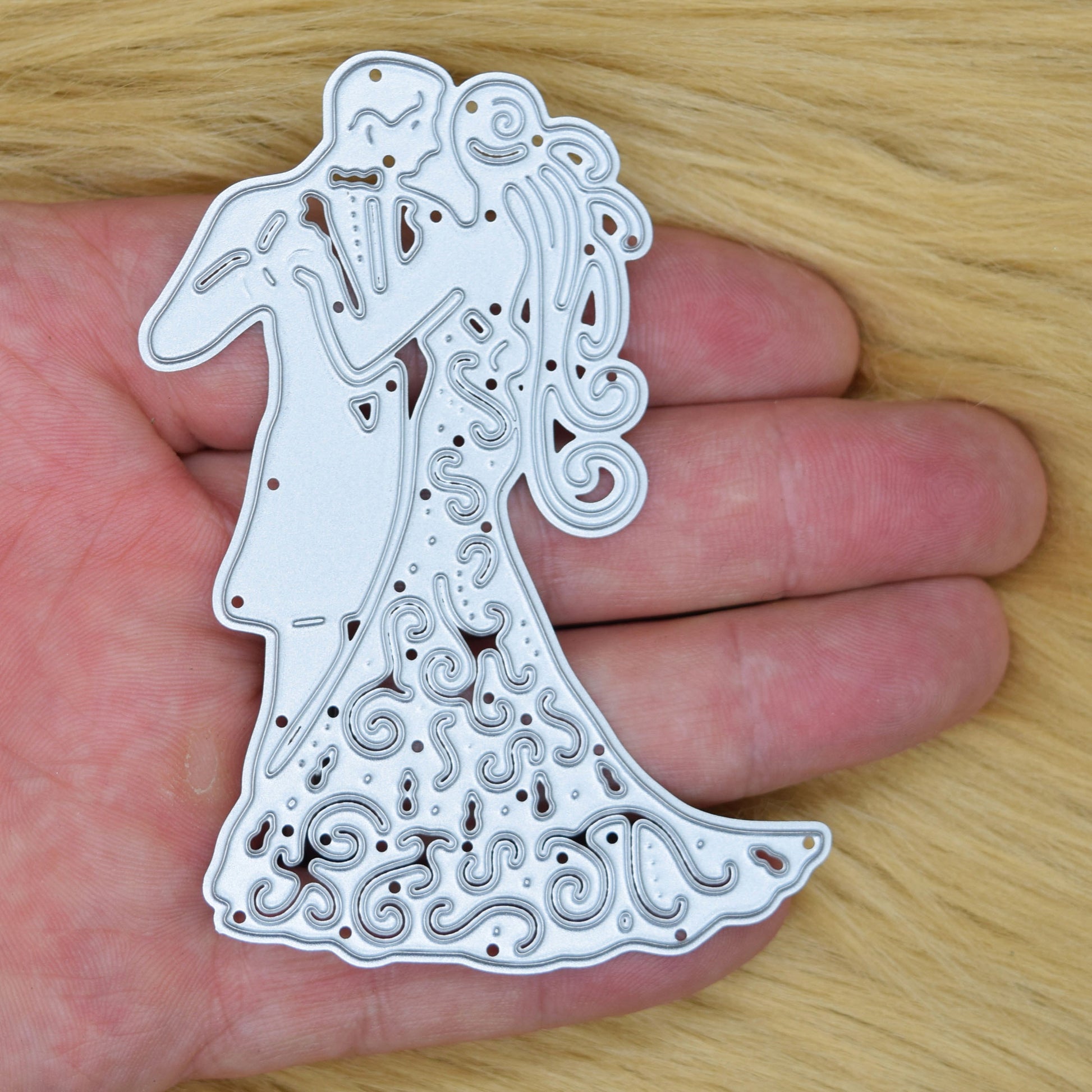 Bride and groom cutting die shown in hand for size reference